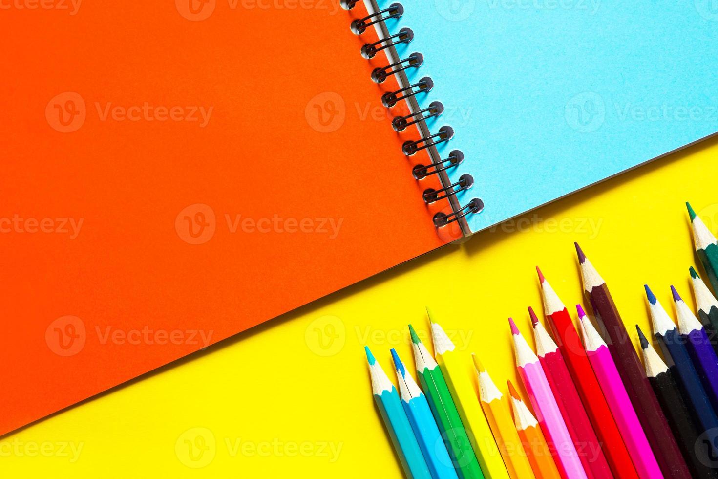 Rainbow palette of colored pencils with a spiral notebook on a yellow background,mock up, flat lay. Back to school, student recruitment, artist, drawing lessons. Copy space. Stationery for creativity photo