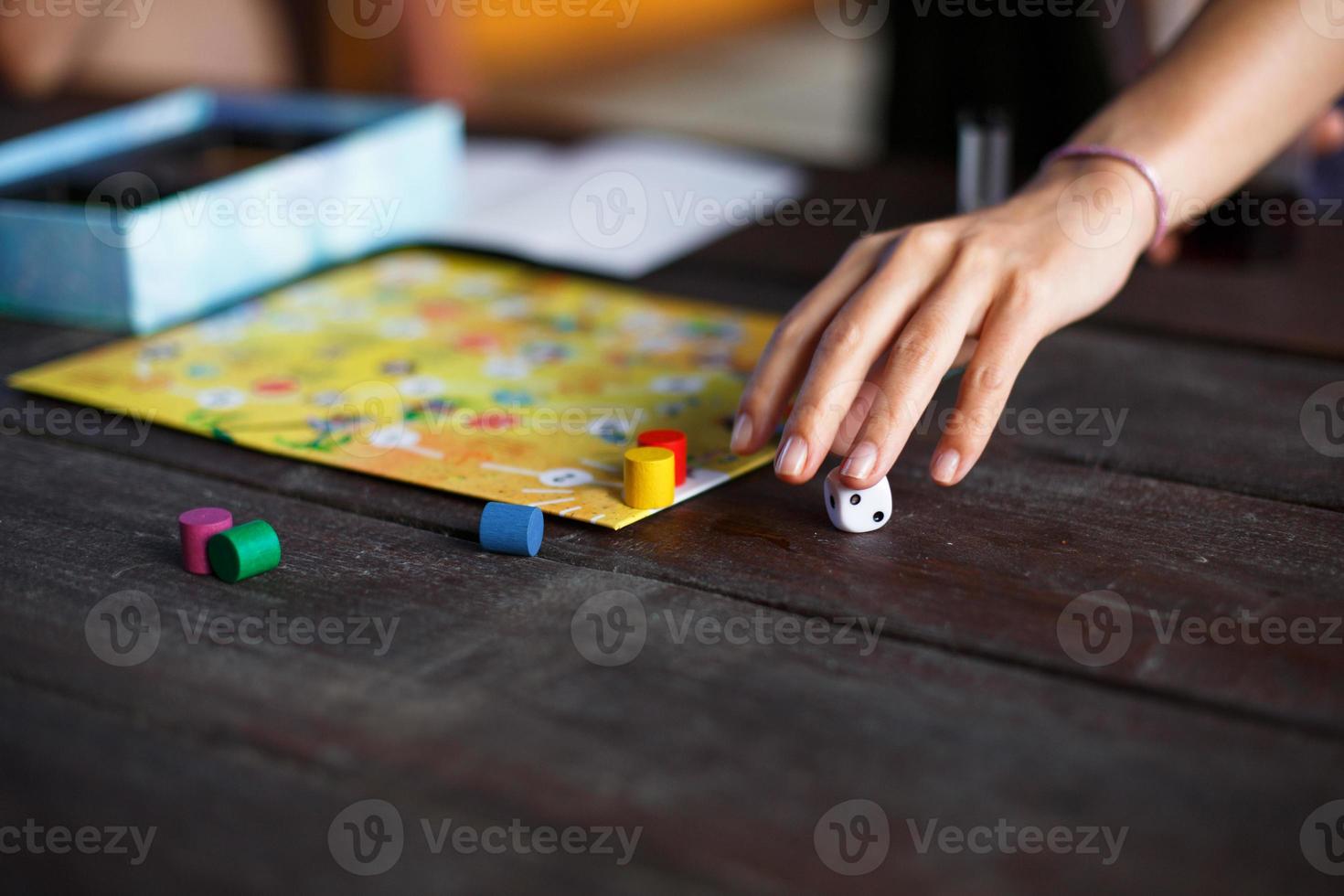 tablero de juego de mesa, fichas, cubo, temporizador en una mesa de madera oscura y manos en el fondo. el concepto de trabajo en equipo, relajación intelectual, evento corporativo, jugar en casa con niños. copie el espacio foto