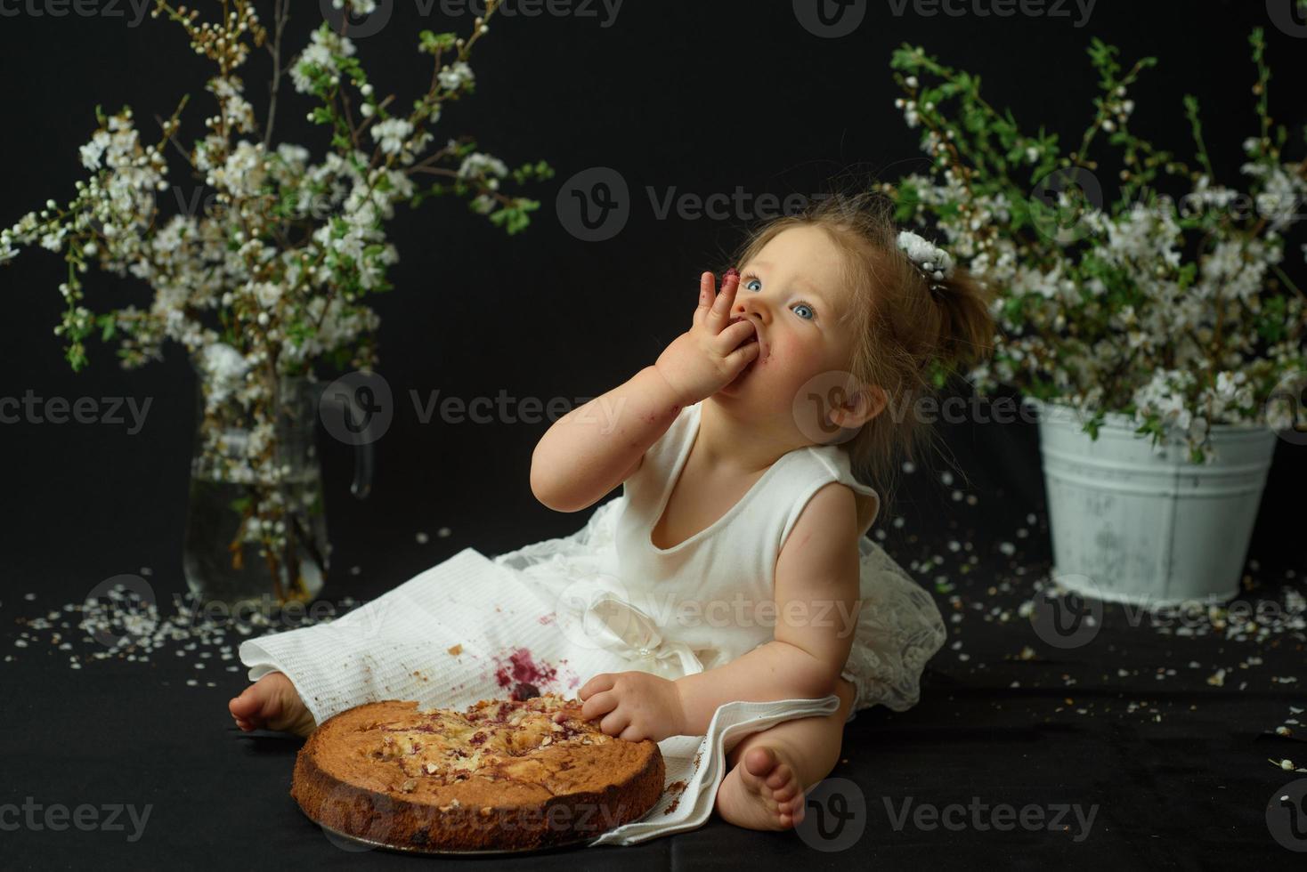 Little girl celebrates her first birthday. Girl eating her first cake. photo