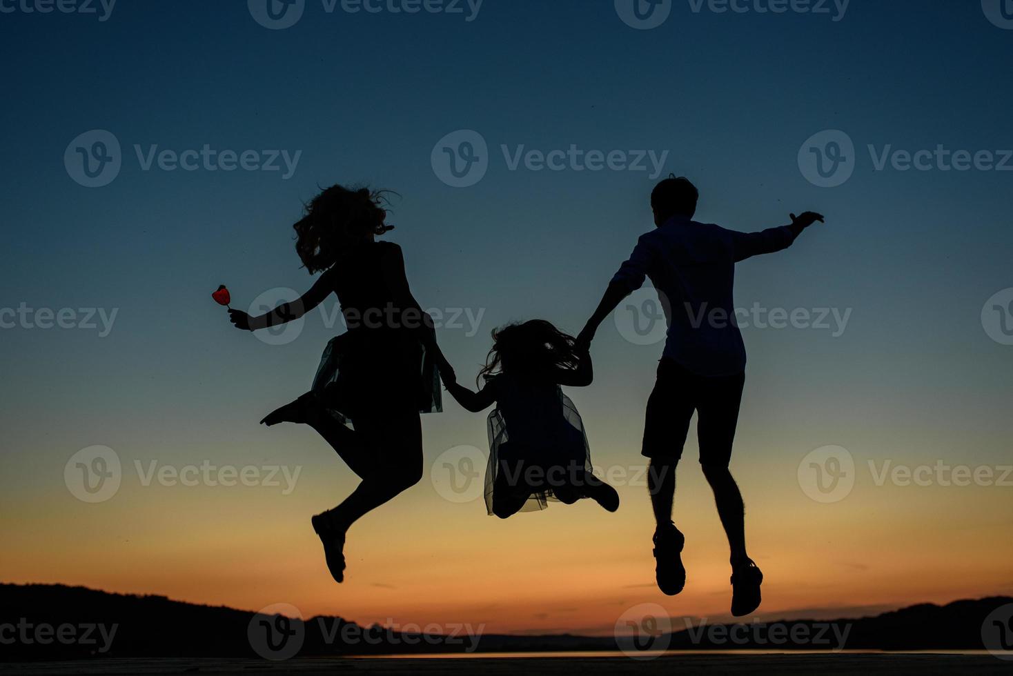 Silhouette of a family while jumping at sunset. photo