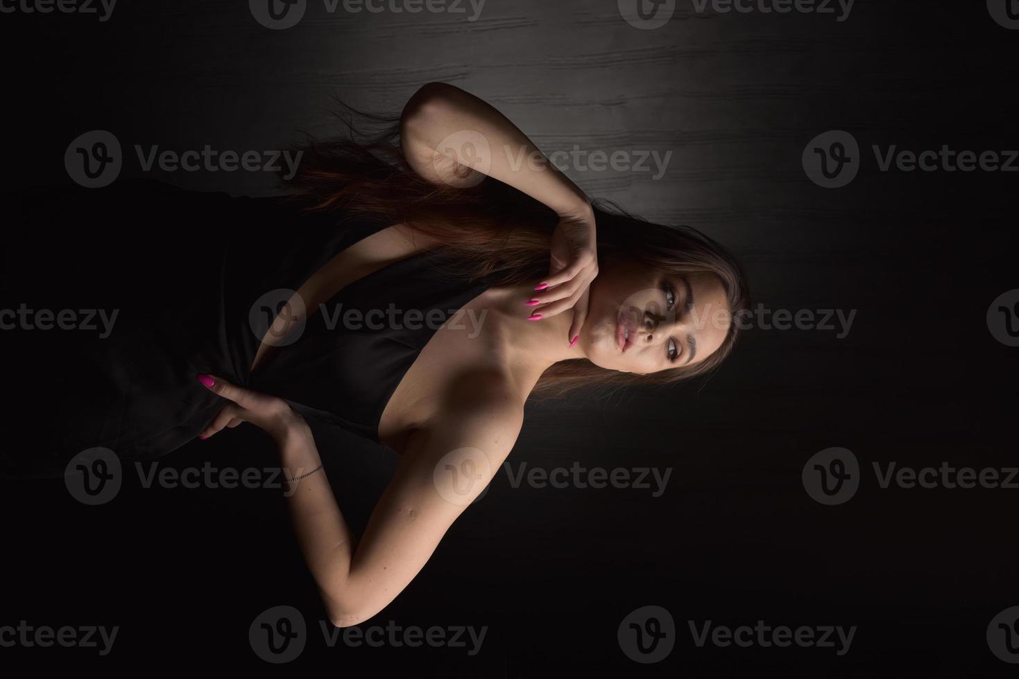 hermosa mujer en vestido negro sobre fondo negro foto