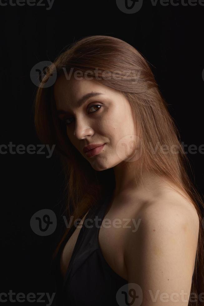 hermosa mujer en vestido negro sobre fondo negro foto