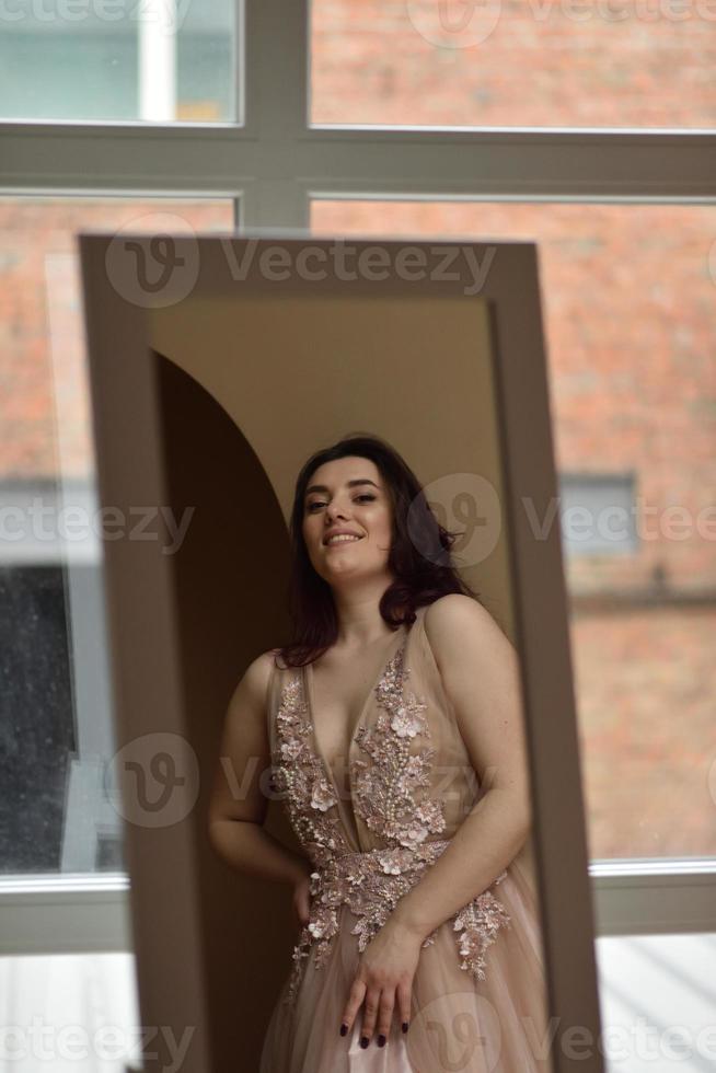 Young girl in dress inside room sits window photo