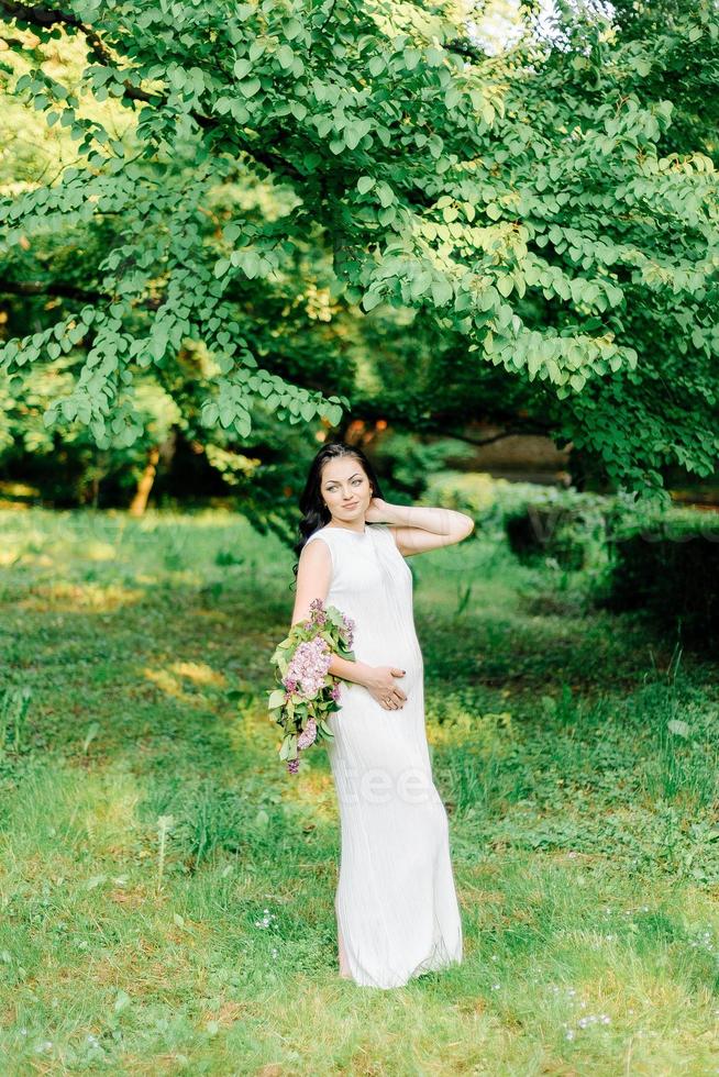 happy pregnant woman in a wreath and a bouquet of wild flowers o photo
