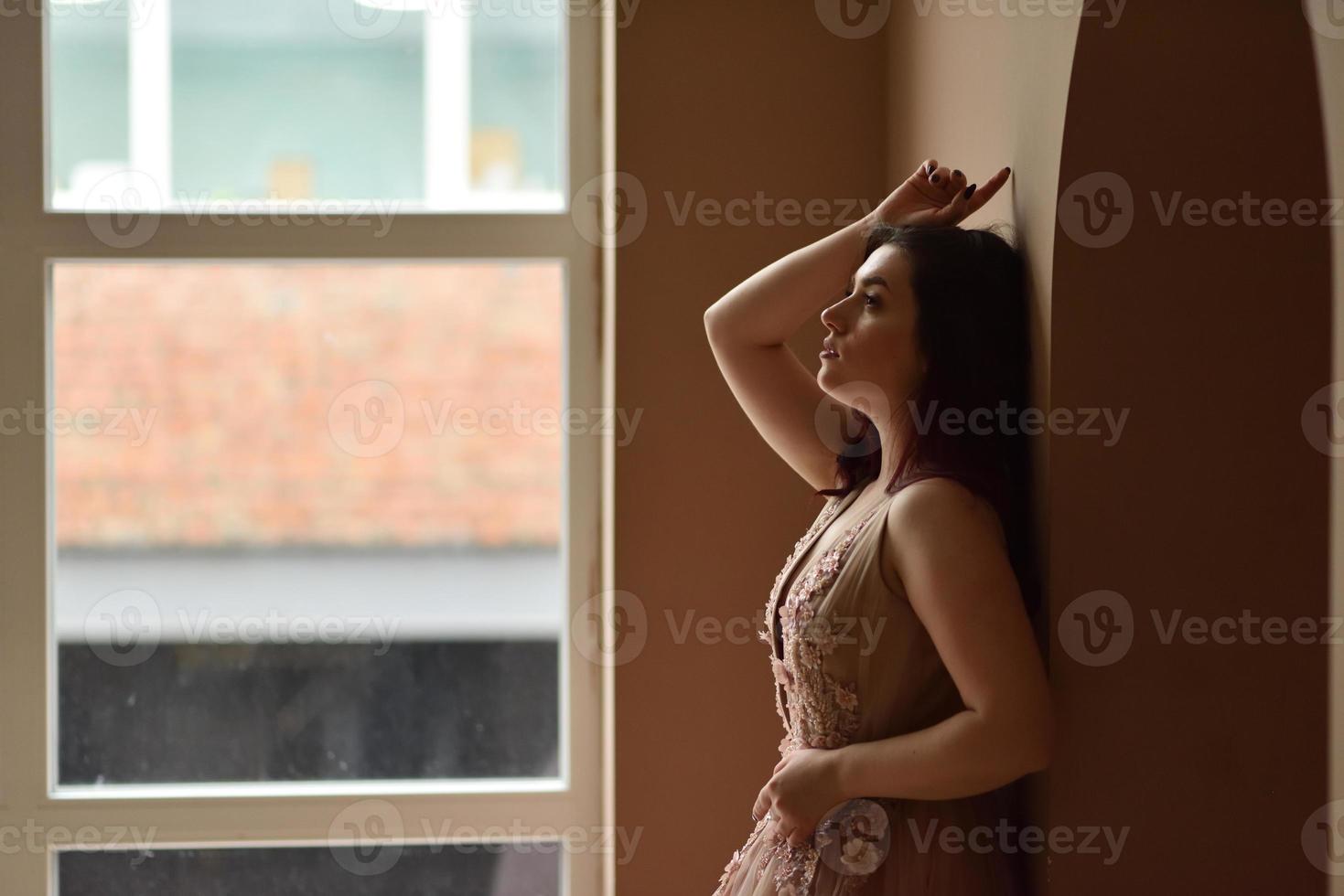 Young girl in dress inside room sits window photo