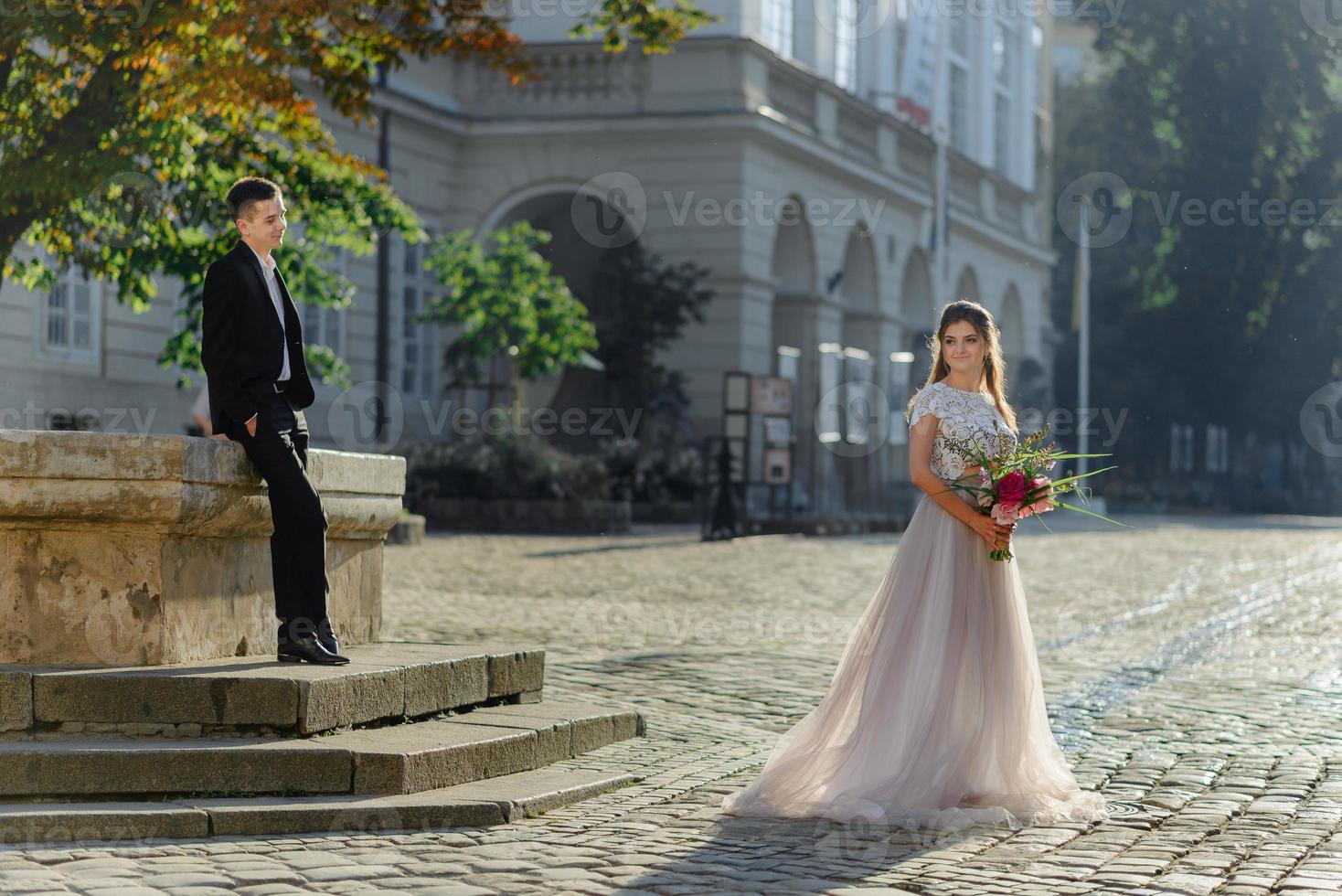 Portrait of beautiful smiling love couple sitting near fountain on a sunny day photo