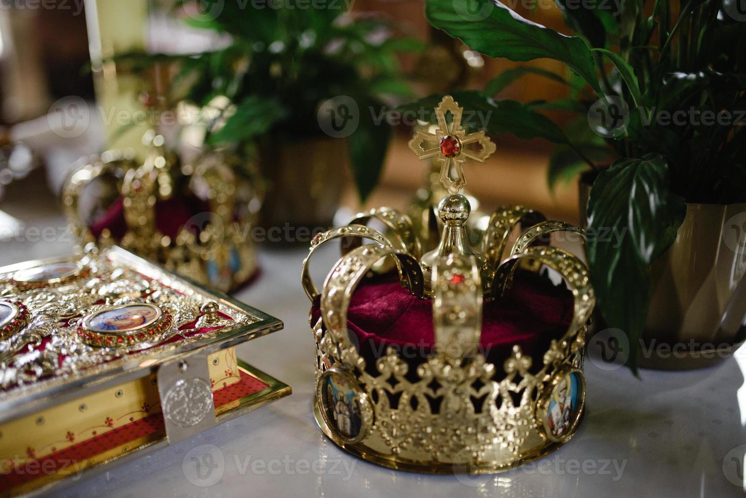 golden crown with gemstones on red napkin on altar in church. traditional wedding ceremony, religion photo