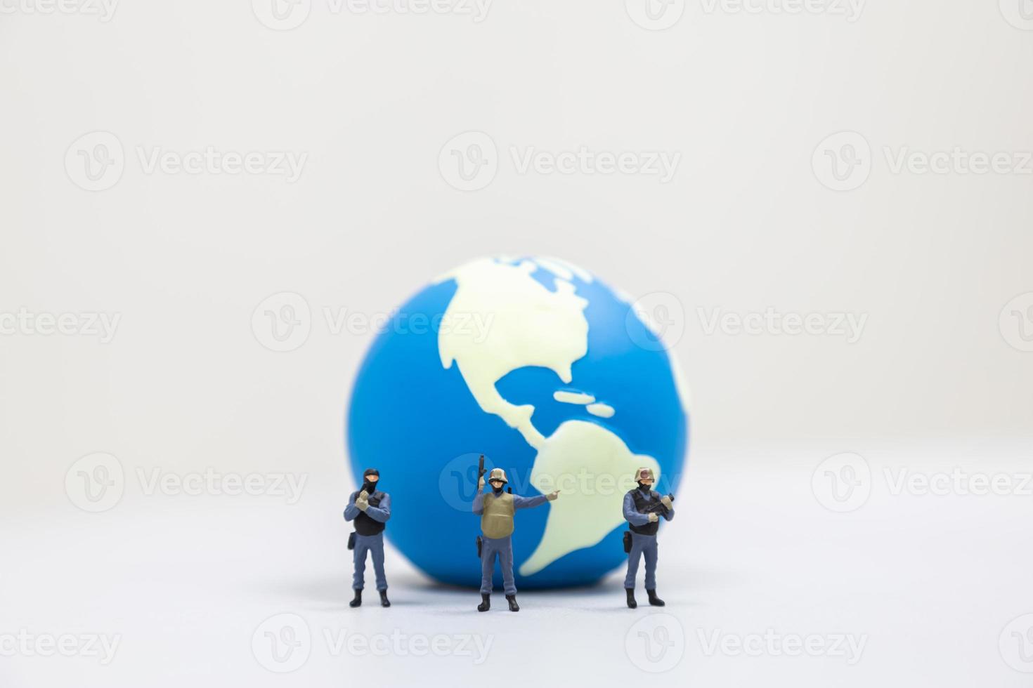 Global Defence and Protection Concept. Close up of group of miniature soldier in with gun standing in front of mini world ball on white background and copy space. photo