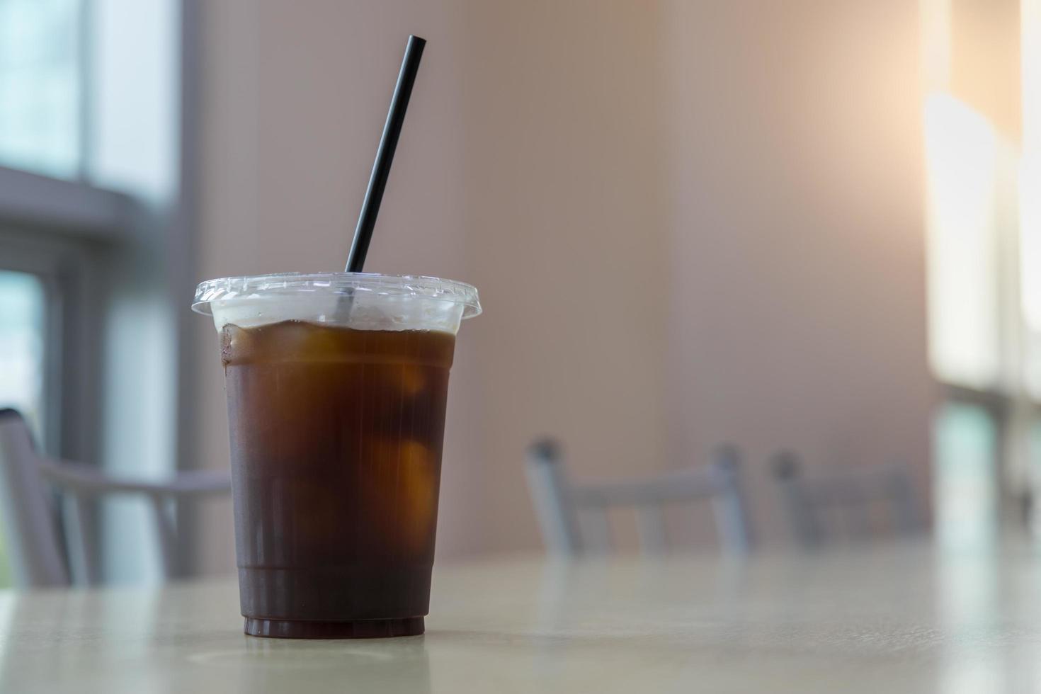 Close up of take away plastic cup of iced black coffee Americano on table with copy sapce. photo