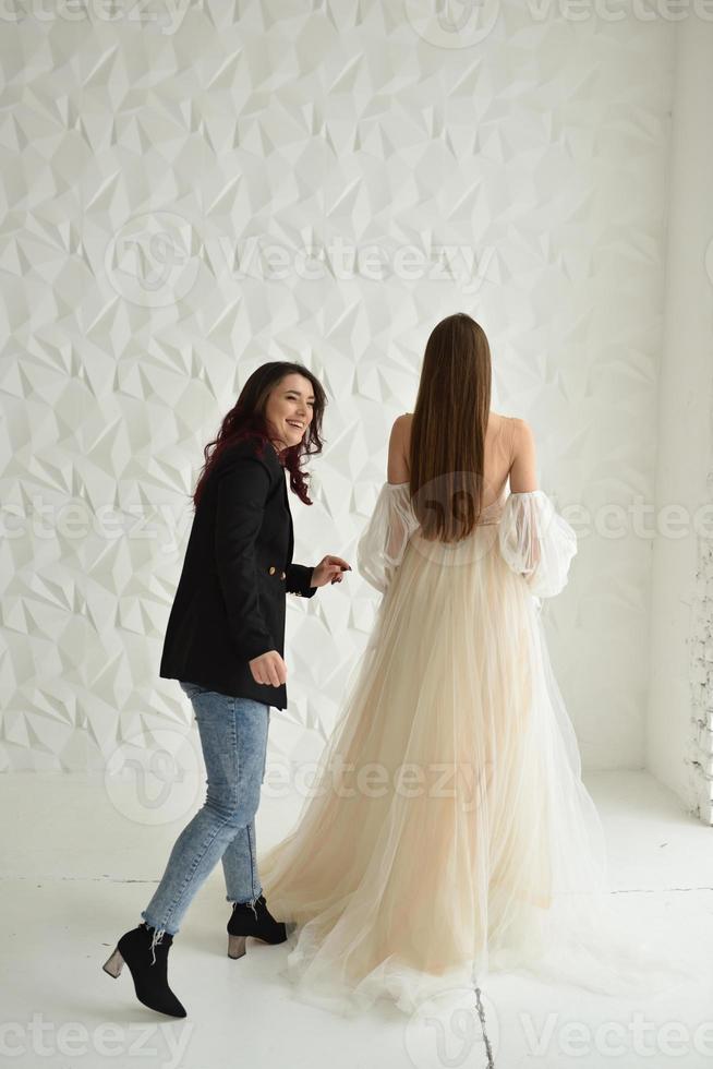 Shop owner helping woman trying on dresses in boutique photo