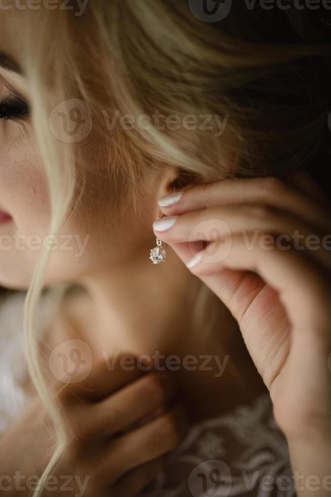 Wedding earrings on a female hand wear, she takes the earrings, the bride fees, morning bride, woman in white dress photo