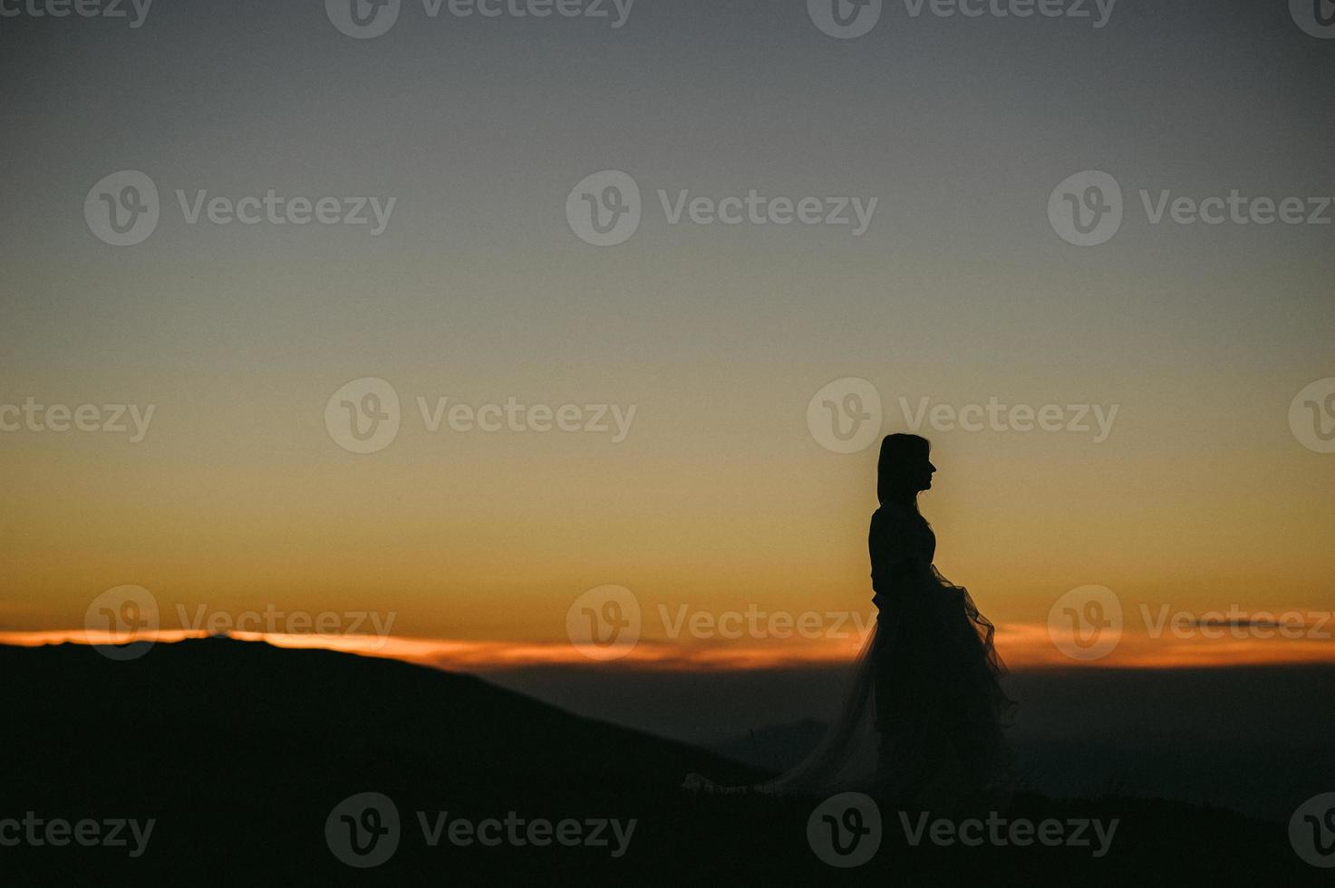 woman in a wedding dress runs across the field toward the mountains photo