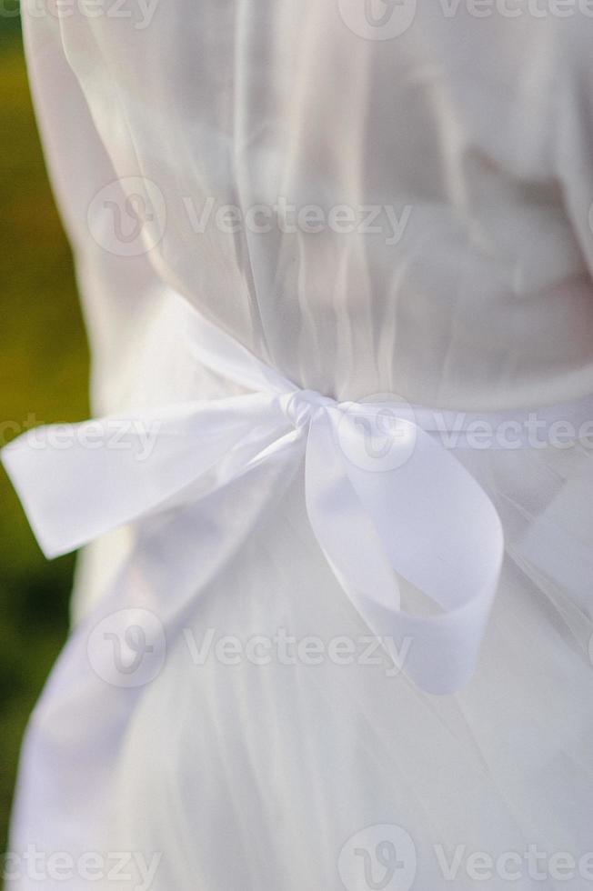 Seamstress buttoning the pretty wedding dress, elegant and bare back. photo