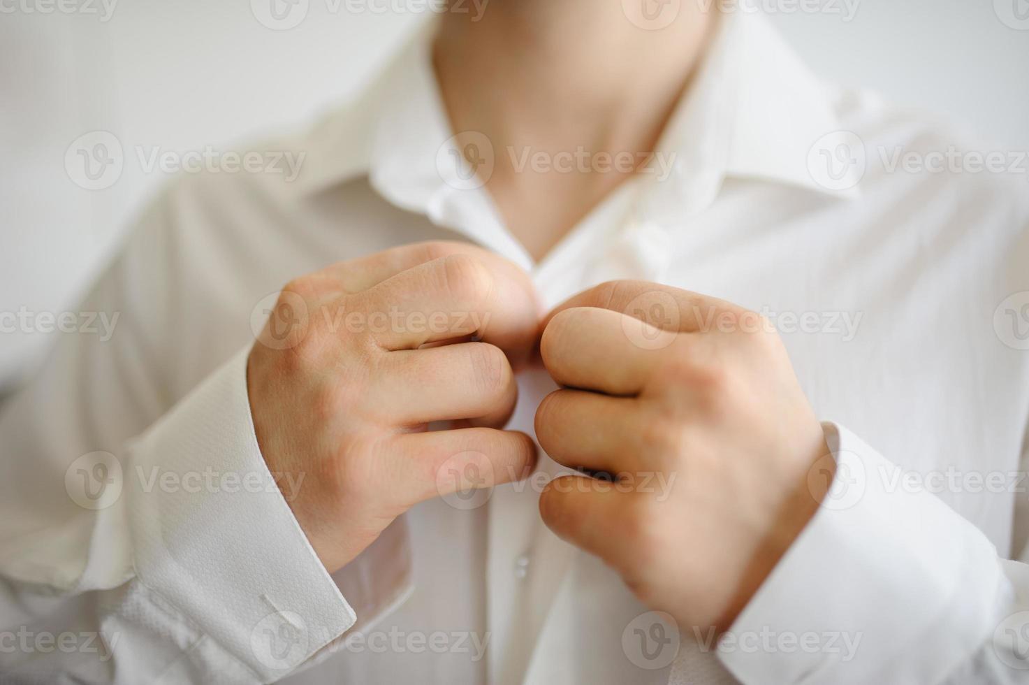 A man fastens buttons on a shirt on a collar. Close-up. photo