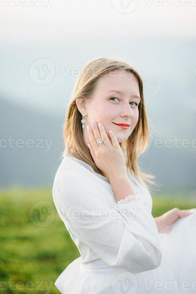 woman in a wedding dress runs across the field toward the mountains photo