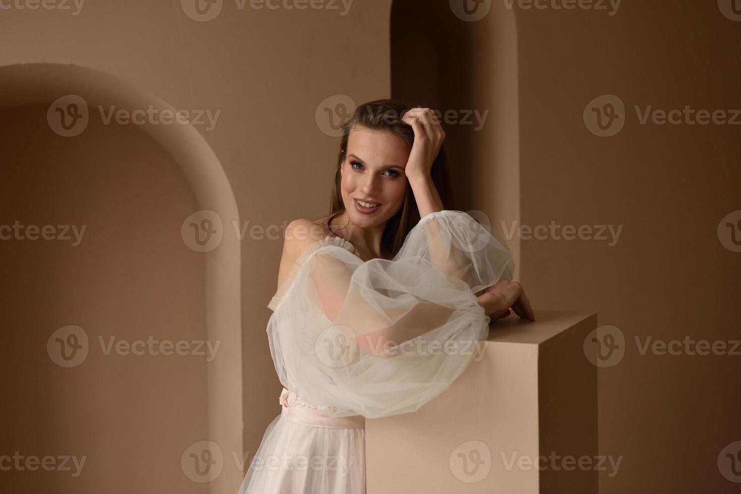 Portrait of a young beautiful bride in full growth. Girl posing in a room near the window. photo