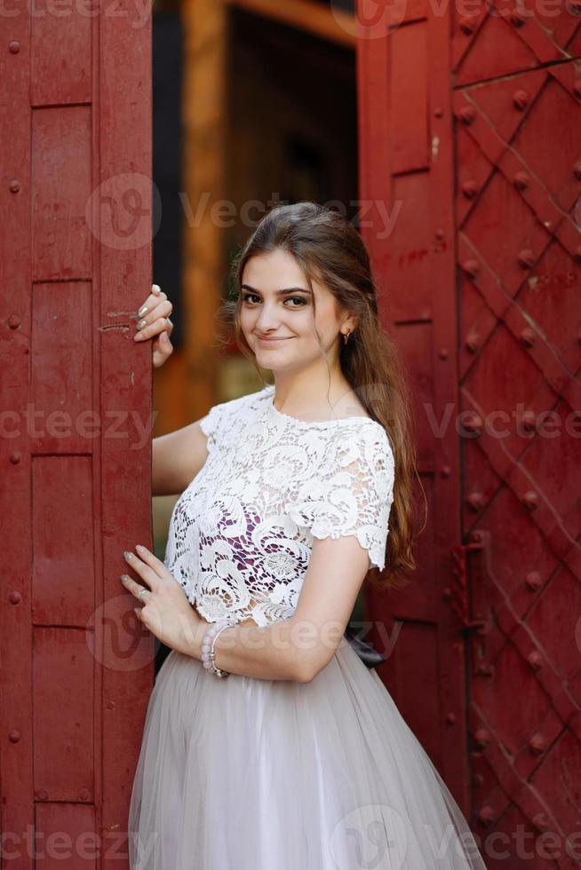 hermoso peinado de maquillaje de boda de retrato de novia, mujer joven hermosa en vestido blanco en casa. serie. foto