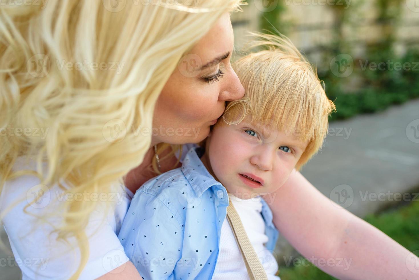 Mom leads her son's hand through the green grass. Both blondes. photo
