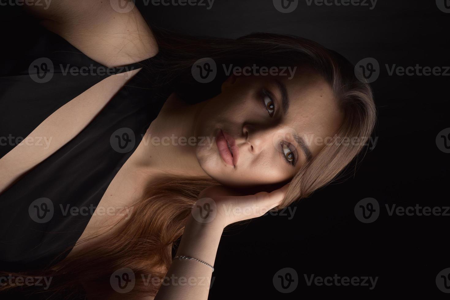 hermosa mujer en vestido negro sobre fondo negro foto