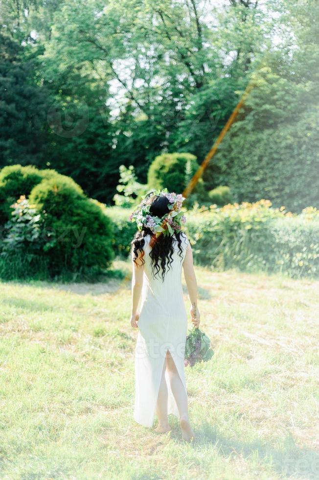 joven embarazada en el jardín floreciente lila de primavera. mirada romántica con sombrero de paja. mujer caucásica con pelo largo y castaño. concepto de nueva vida de la naturaleza y el ser humano. esperando bebe foto