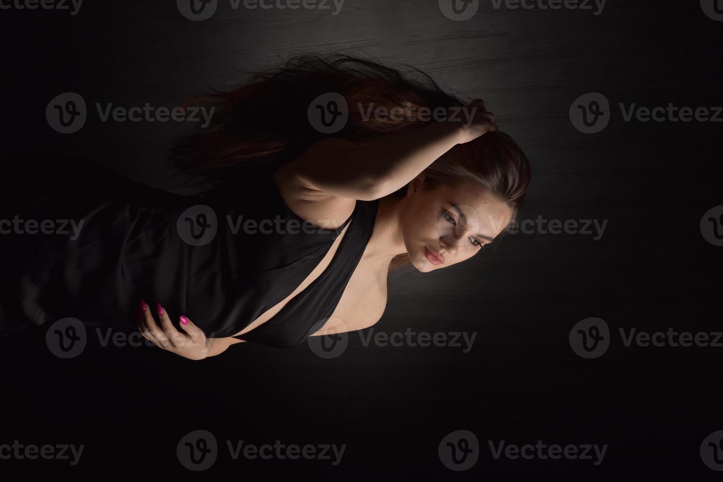 hermosa mujer en vestido negro sobre fondo negro foto