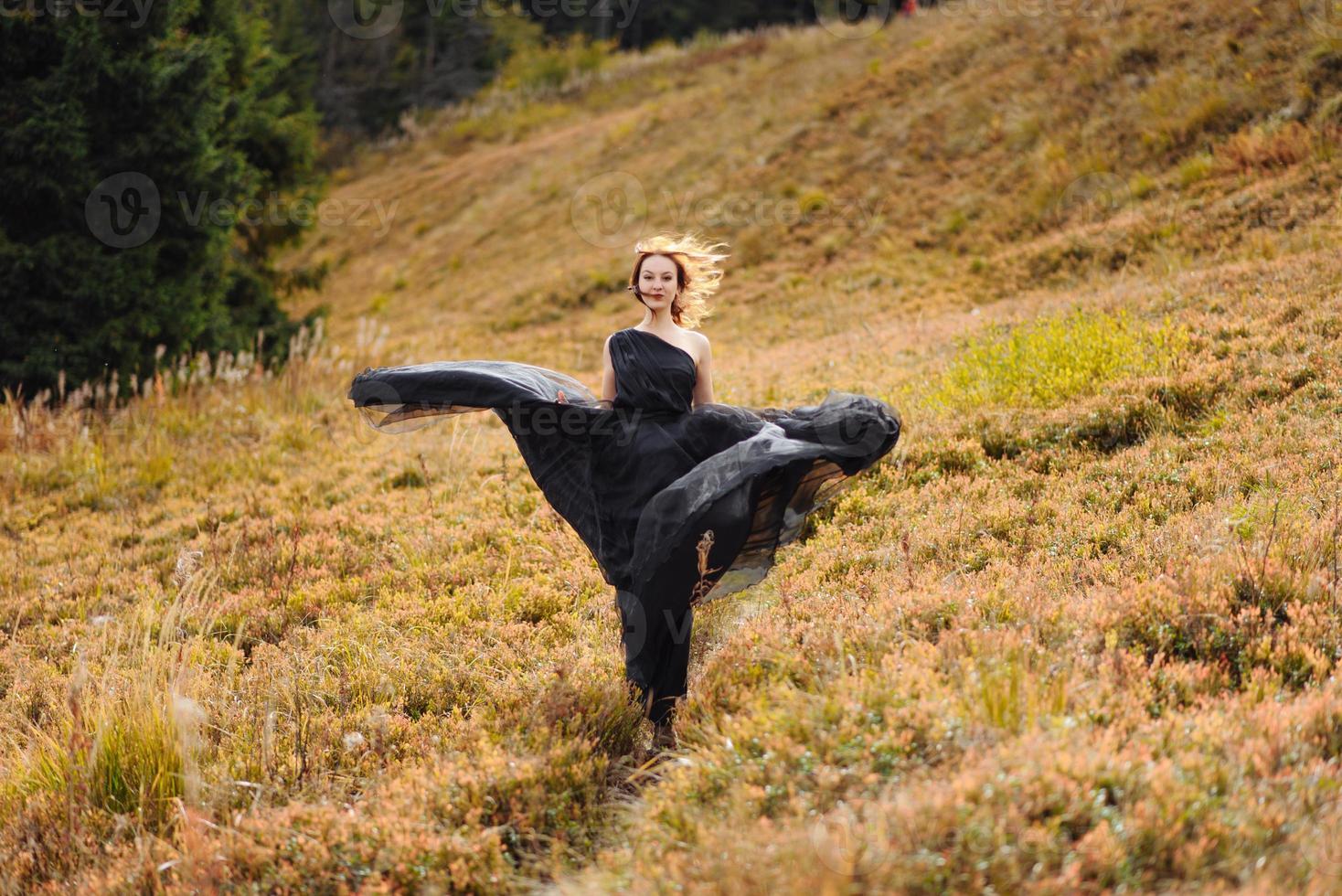 la novia con un vestido negro sobre un fondo de montañas otoñales. foto