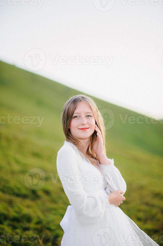 woman in a wedding dress runs across the field toward the mountains photo