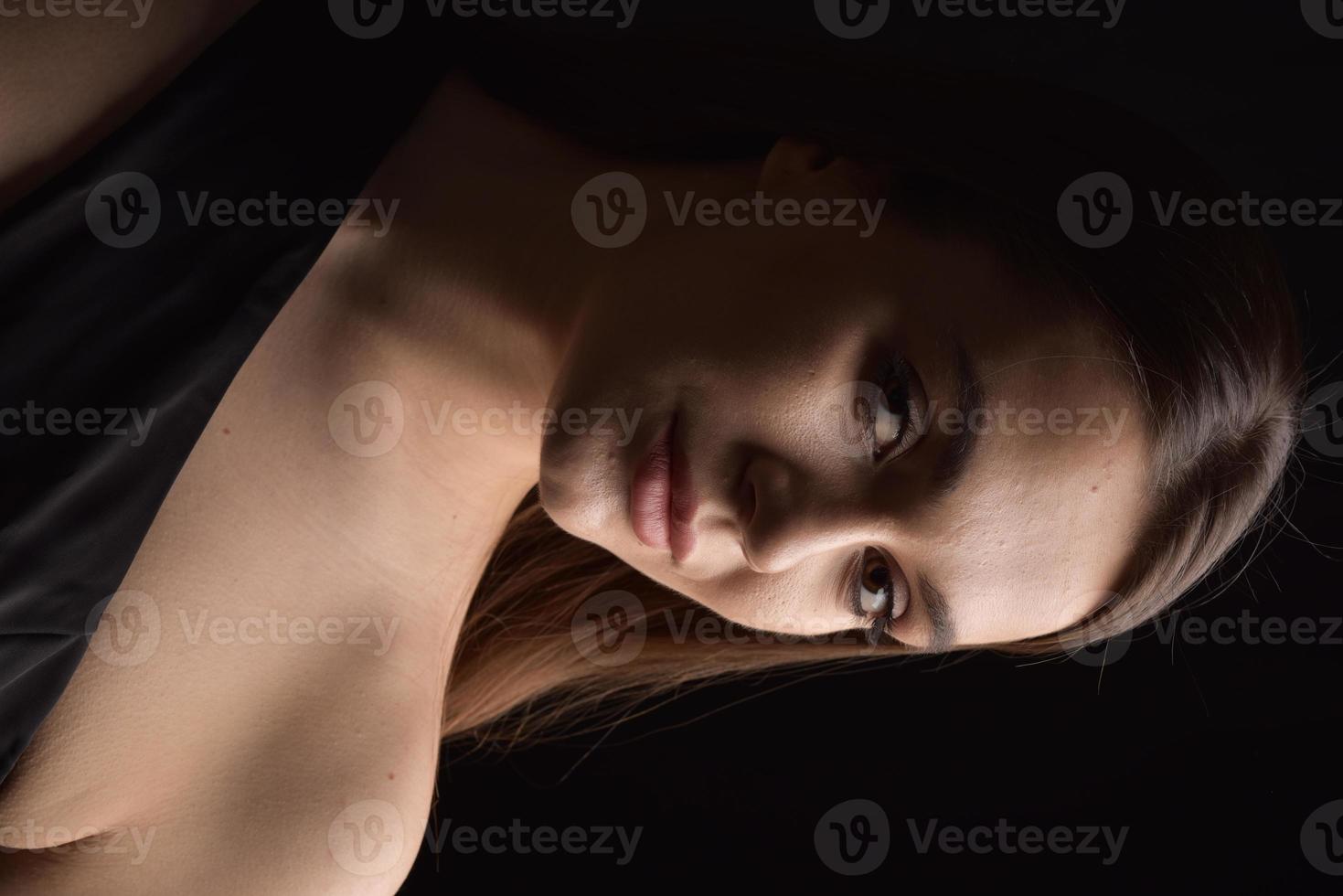 hermosa mujer en vestido negro sobre fondo negro foto