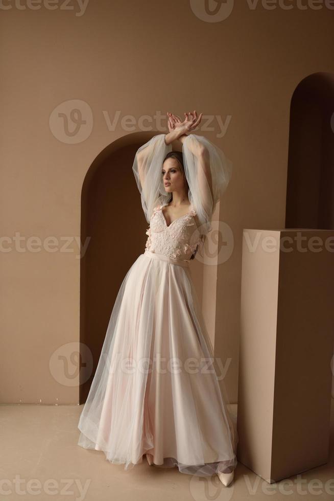 Portrait of a young beautiful bride in full growth. Girl posing in a room near the window. photo