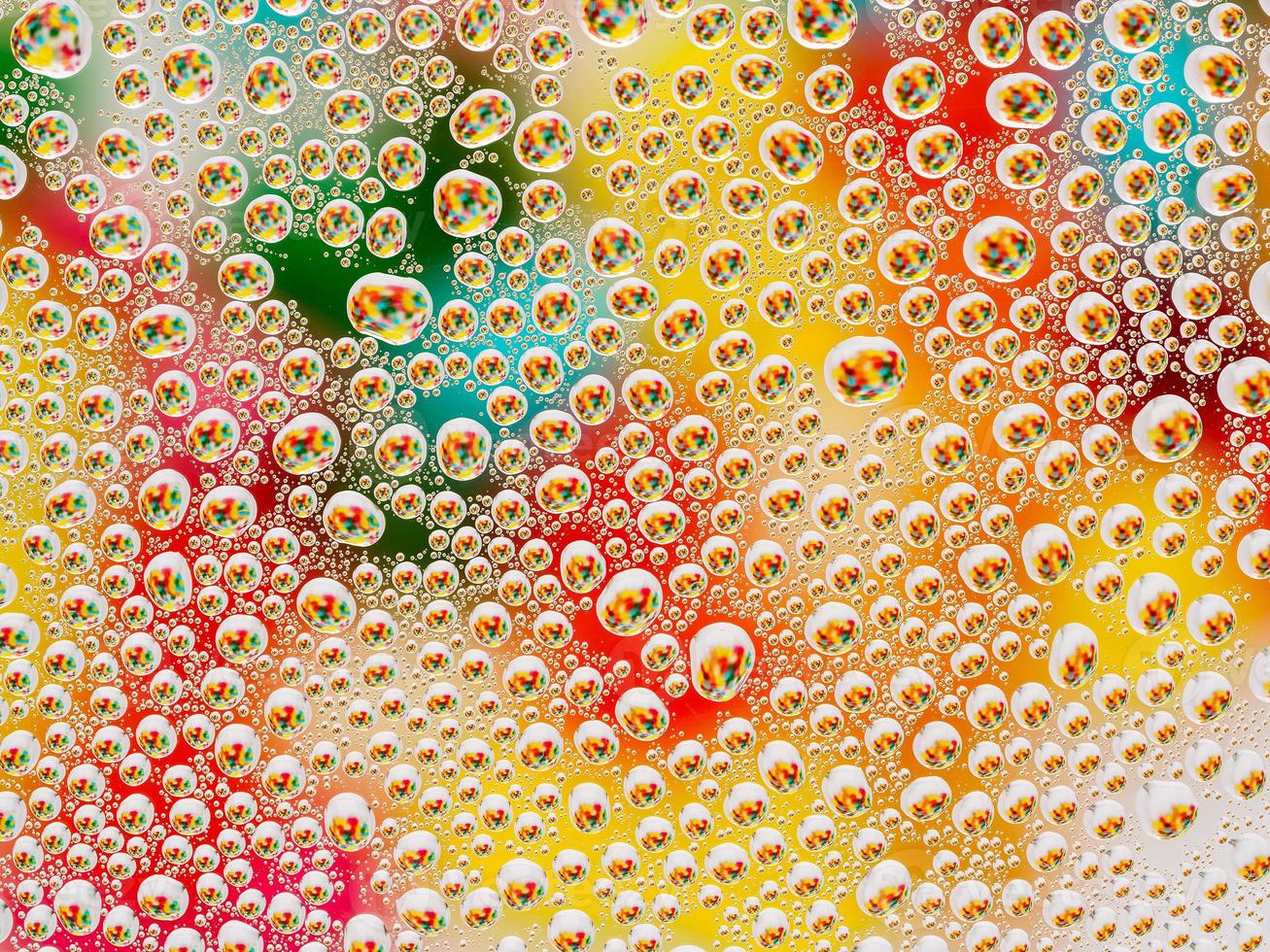 Abstract colorful vivid background with large and small spherical convex drops of water on the glass. Macro, top view, close up. photo