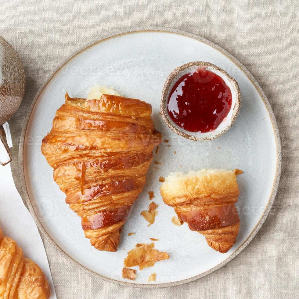 One delicious croissants on plate, hot drink in mug. Morning French breakfast with fresh pastries photo