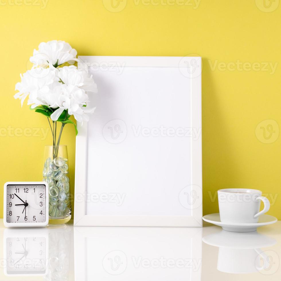 White frame, flower in vase, cup with tea or coffee, clock on wh photo