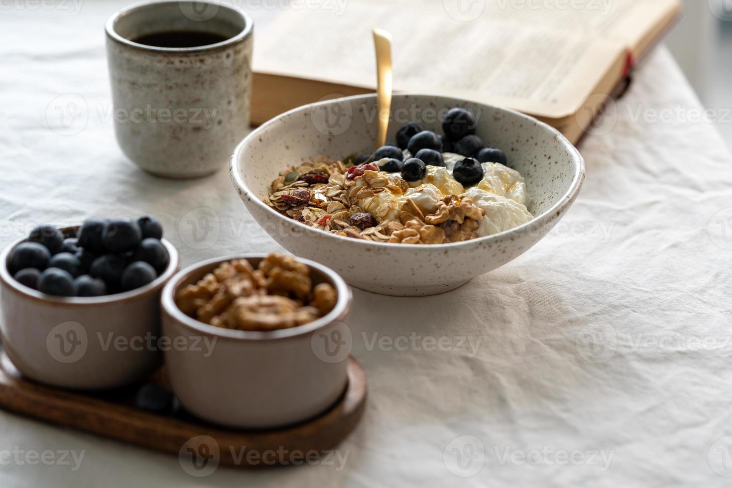 leyendo un libro y comiendo un desayuno de estilo de vida saludable con muesli de granola y yogur foto