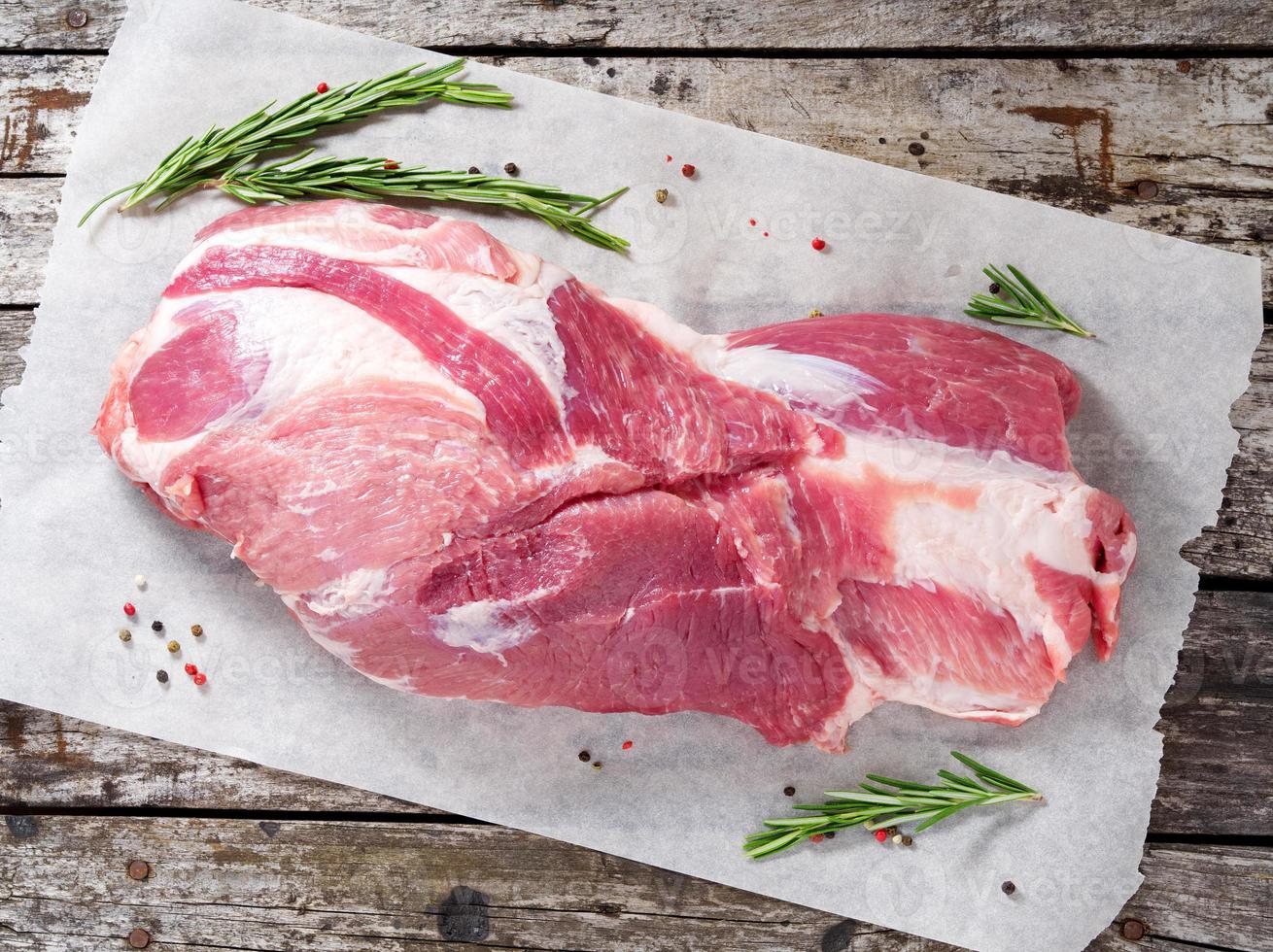 raw fresh pork neck, whole big piece on white parchment paper, on grey old wooden table photo