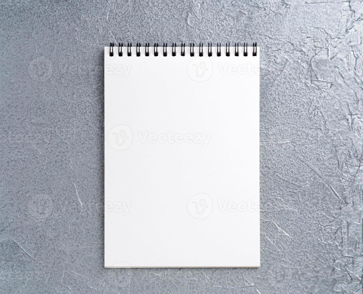 blank sheet of notebook with a spiral on a neutral gray textured silver metallic background photo