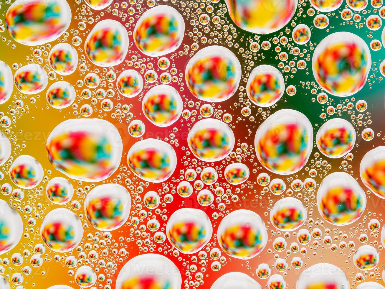 Abstract colorful vivid background with large and small spherical convex drops of water on the glass. Macro, top view, close up. photo