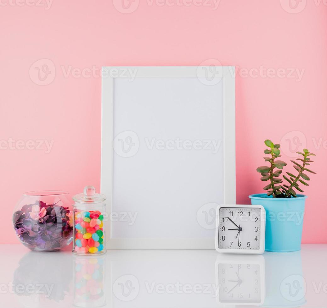 Blank white frame and plant cactus, sweet candy in jar on white photo