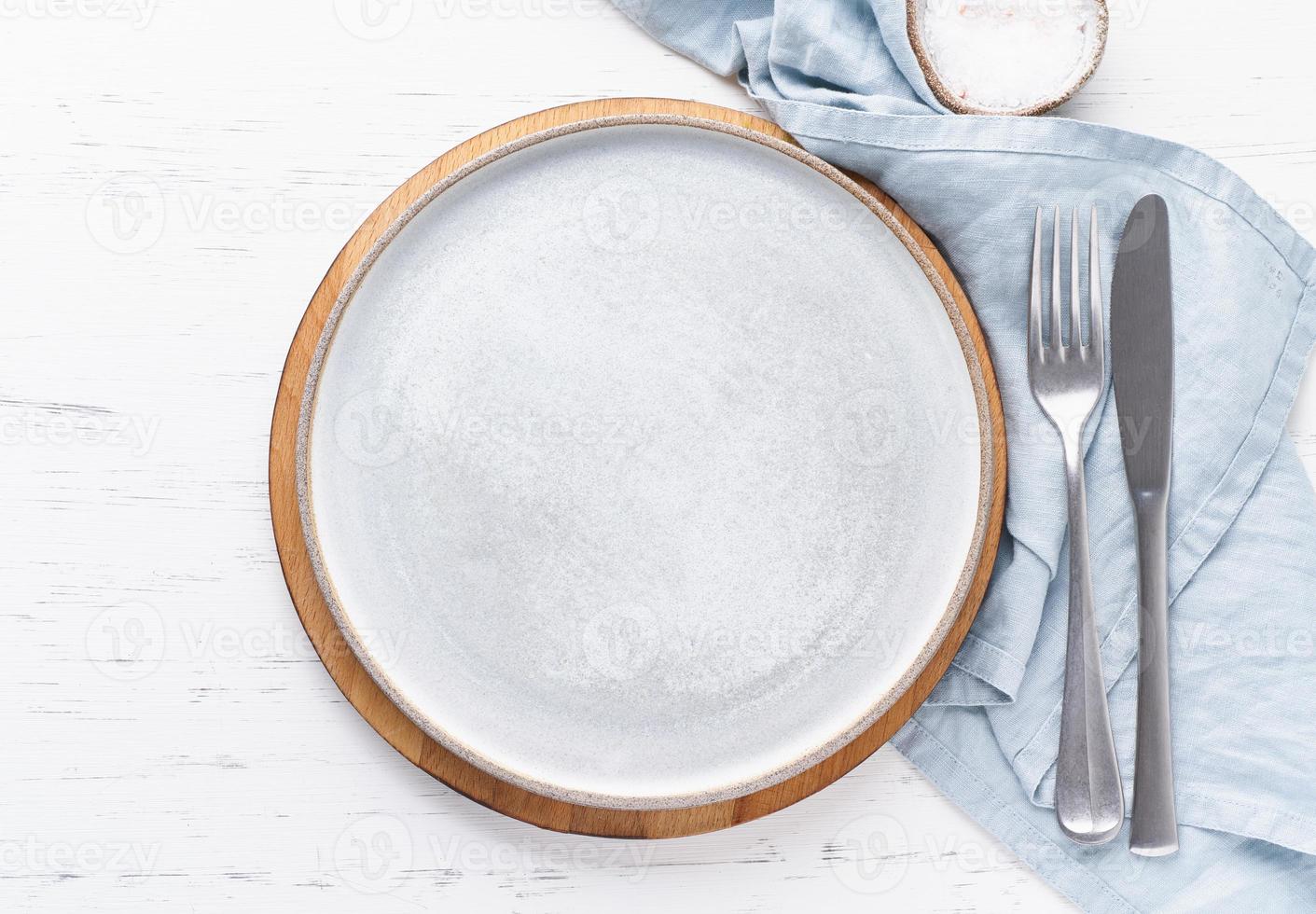 Clean empty white ceramic plate on white stone table, copy space, mock up, top view. photo