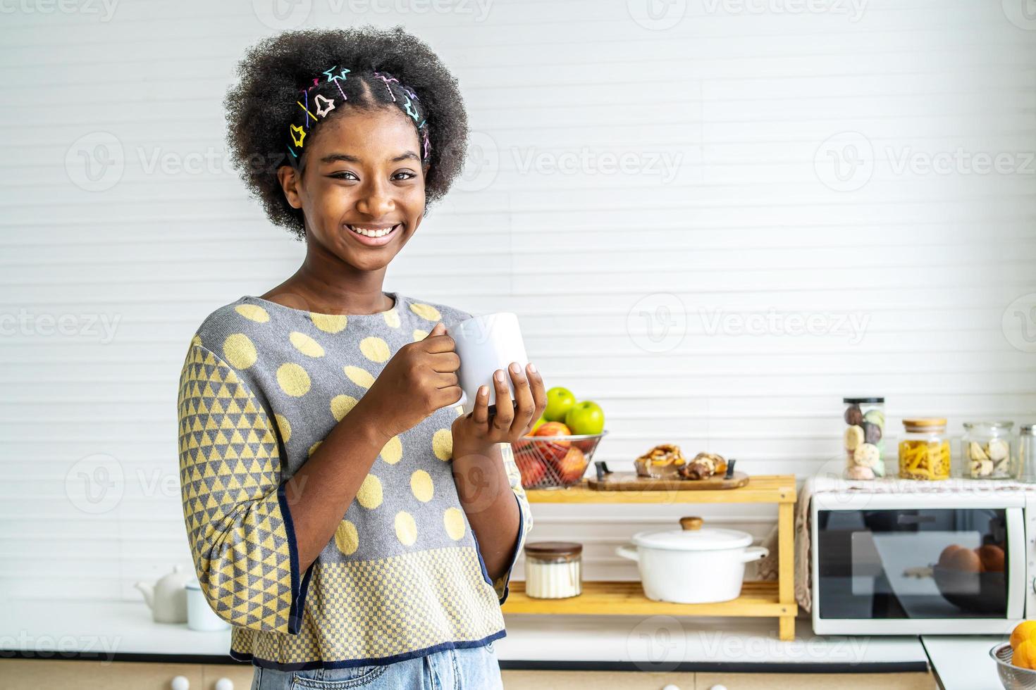 Cheerful young Black woman in loungewear drinking cup of morning coffee in  her kitchen and laughing at funny memes on smartphone screen Stock Photo -  Alamy