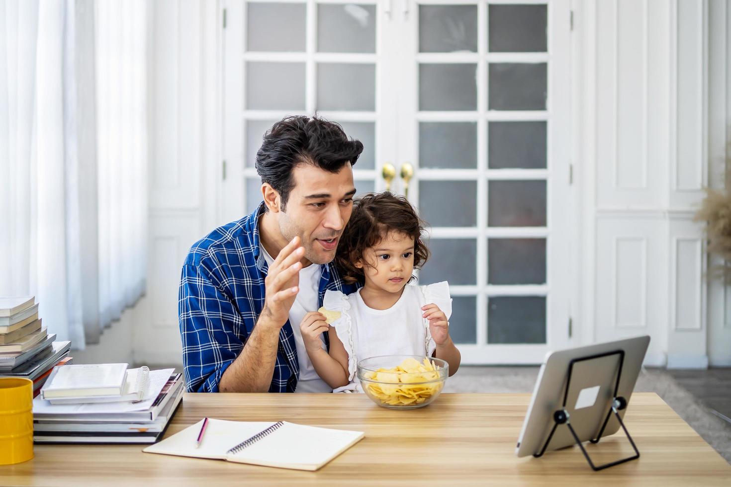 Young attractive father and little cute daughter online together with her mother in video conference with digital tablet for a online talking in video call for social distancing photo