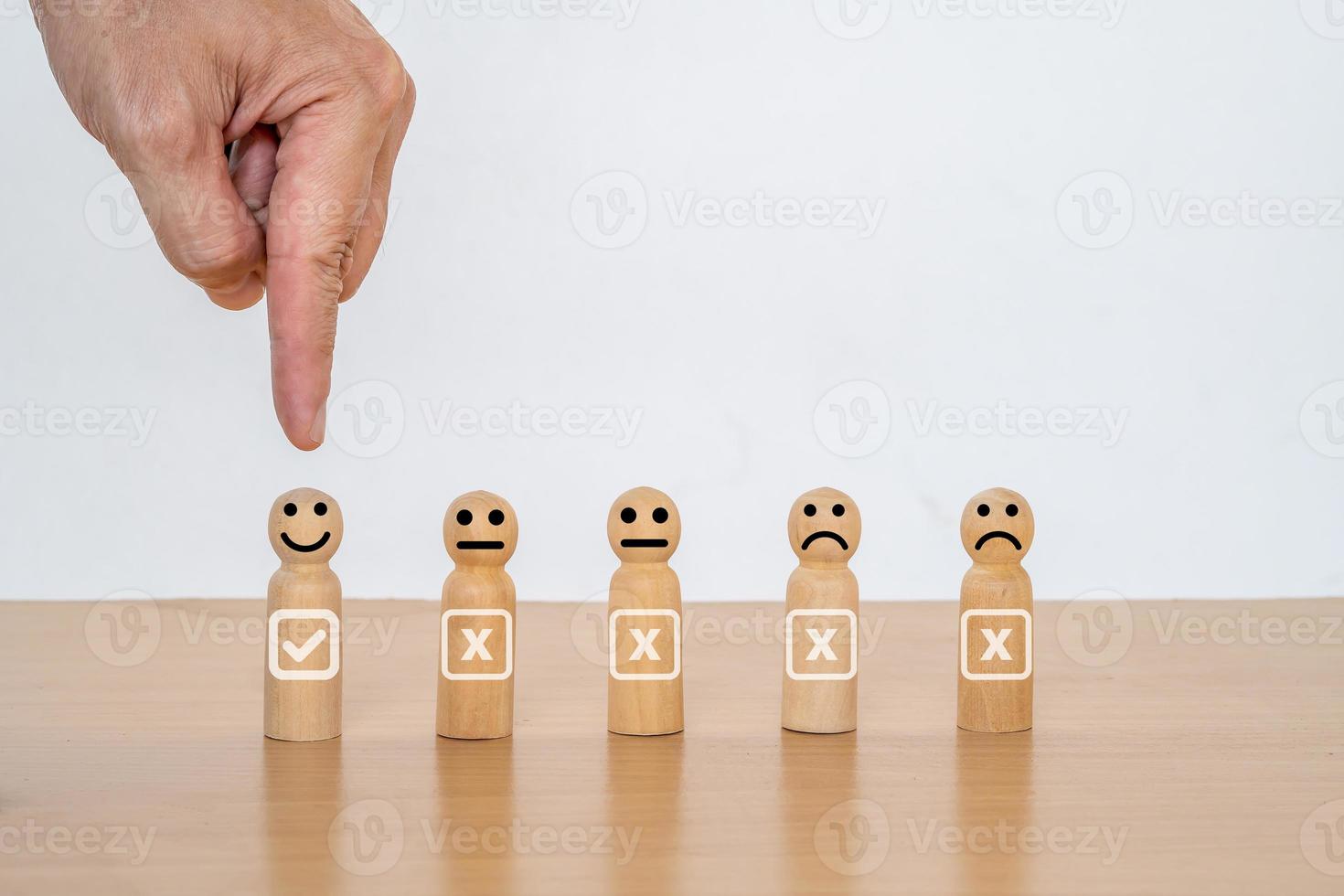 primer plano de la mano de un hombre de negocios que elige una cara sonriente en una muñeca de madera, los mejores servicios comerciales excelentes que califican la experiencia del cliente. concepto de encuesta de satisfacción, satisfacción de 5 estrellas. foto