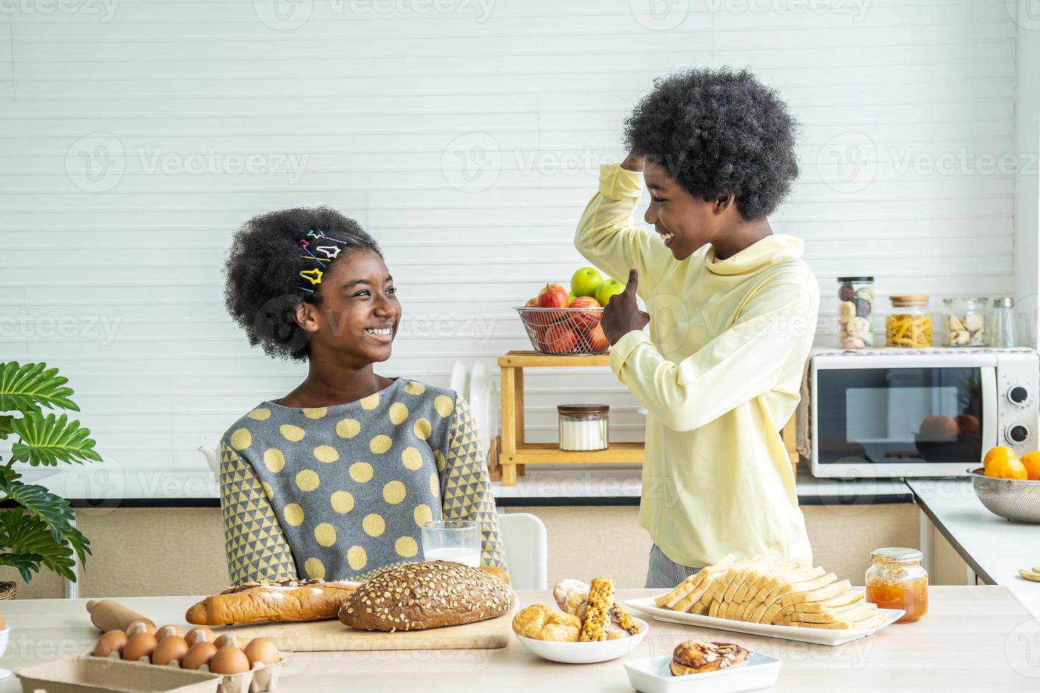 Two cute adorable siblings african american children having breakfast with milk at kitchen,Portrait of happy brother drinking milk showing bicep to tell with his sister, Food and drink health care photo