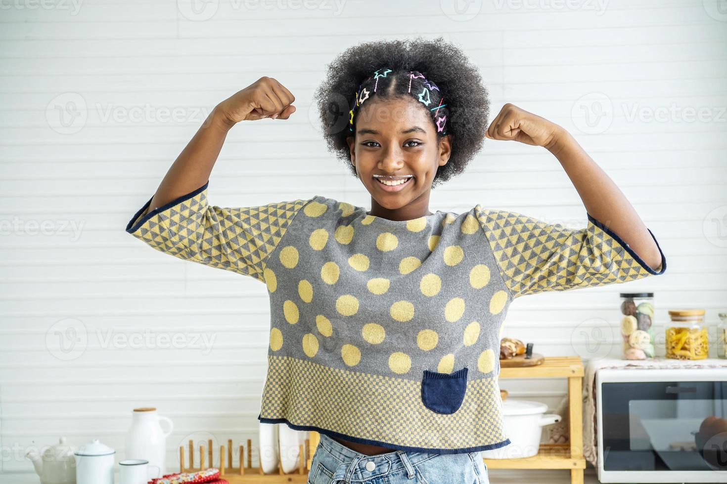 Young happy woman african american afro hair standing and  making strong hand while drinking a milk for breakfast with fun photo
