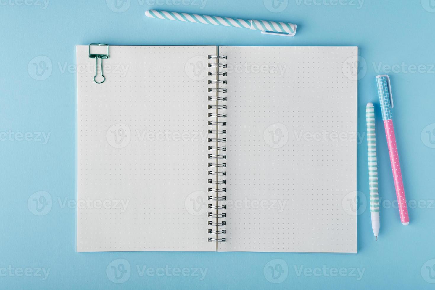Blank notepad page in bullet journal on bright blue office desktop photo