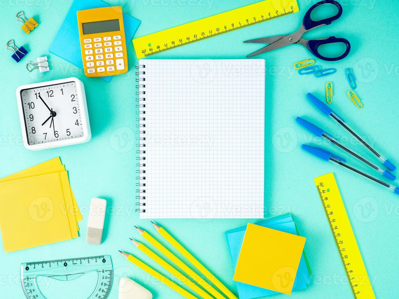 Top view of modern bright blue office desktop with notebook in a cage, school supplies on table, empty space for text. photo