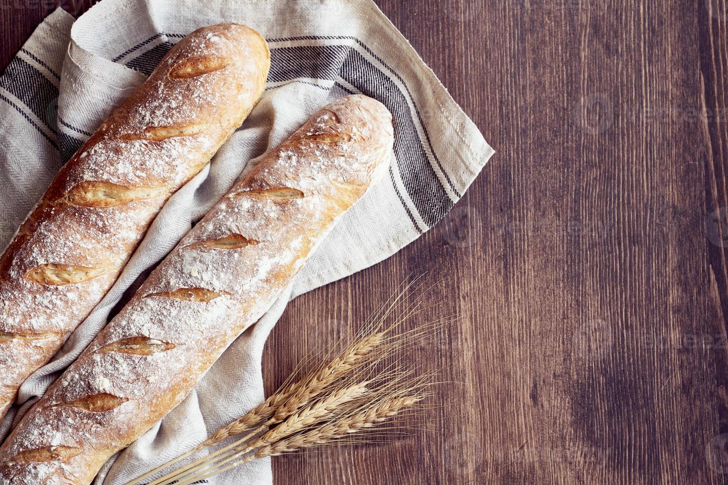 Fresh baked homemade crusty bread baguette. Two loaves on linen towel photo