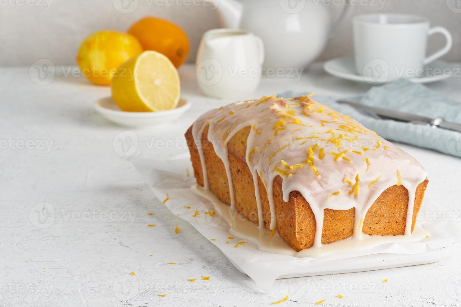 Lemon bread coated with sugar sweet icing. Whole loaf. White background, side view, copy space photo