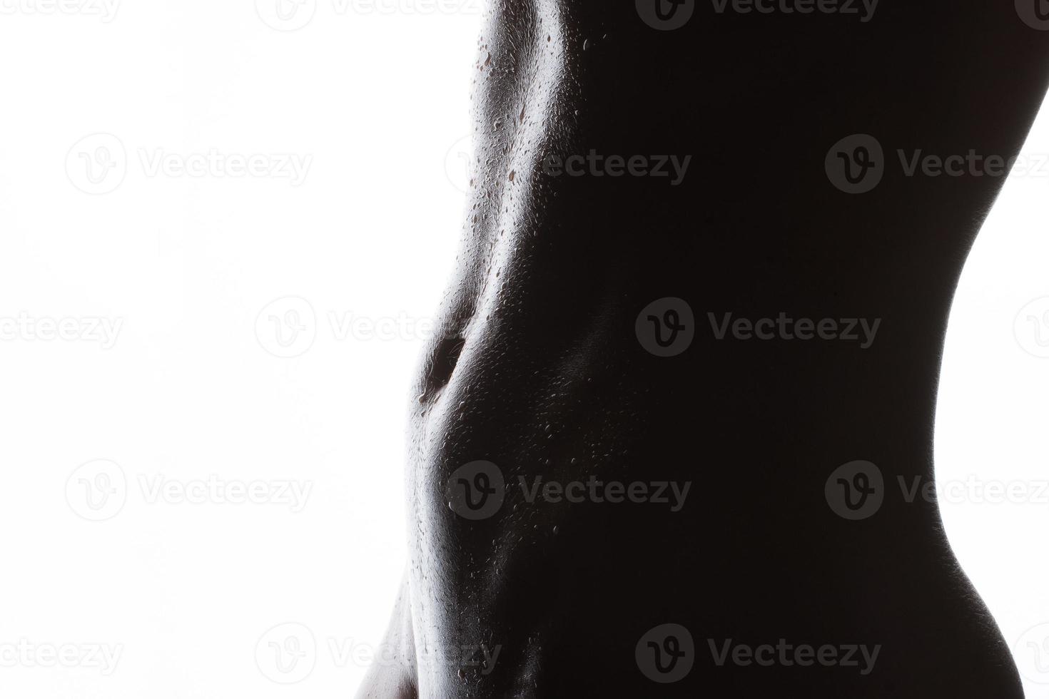 female athletic figure.body and abdominal press with water drops close-up on a white background. photo