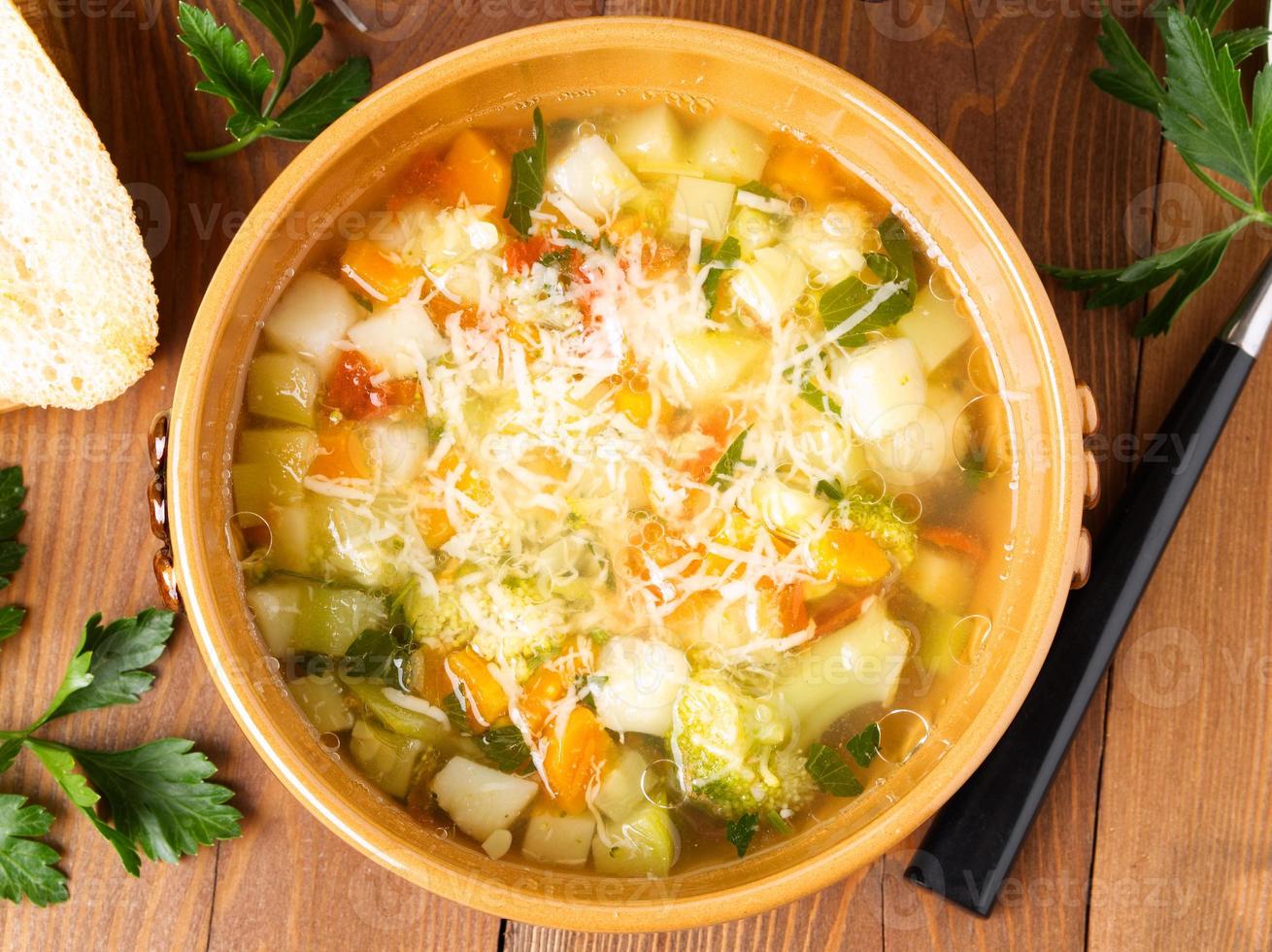 bowl of minestrone soup with toast on rustic wooden background, top view. photo
