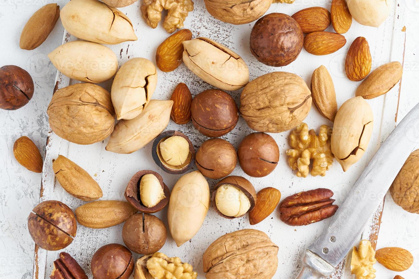 Mix of nuts - walnut, almonds, pecans, macadamia and knife for opening shell photo